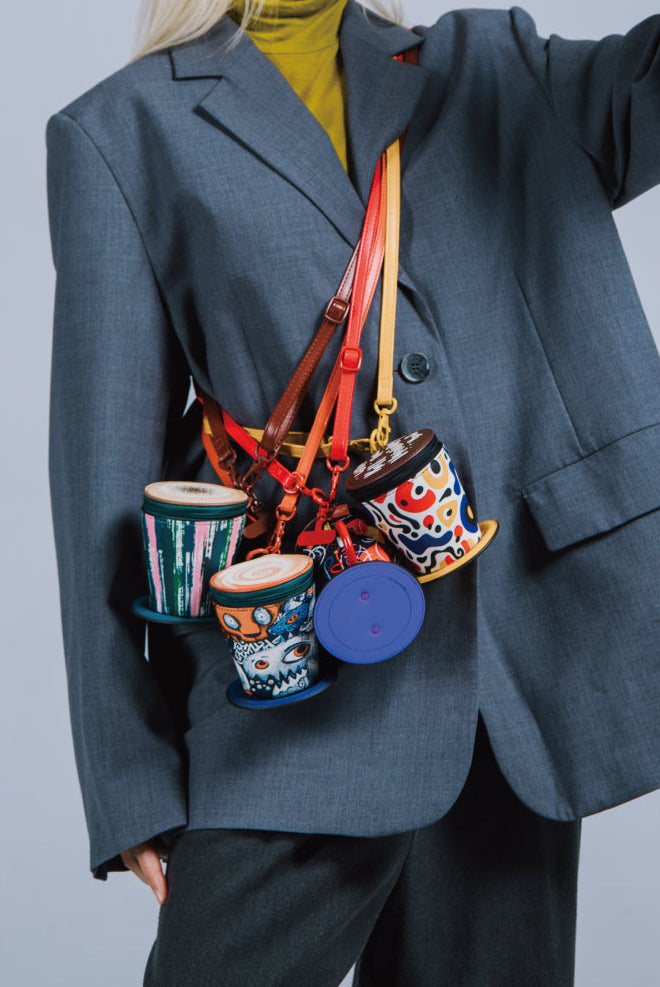 Person wearing a gray coat with a colorful bag featuring various cups and containers.