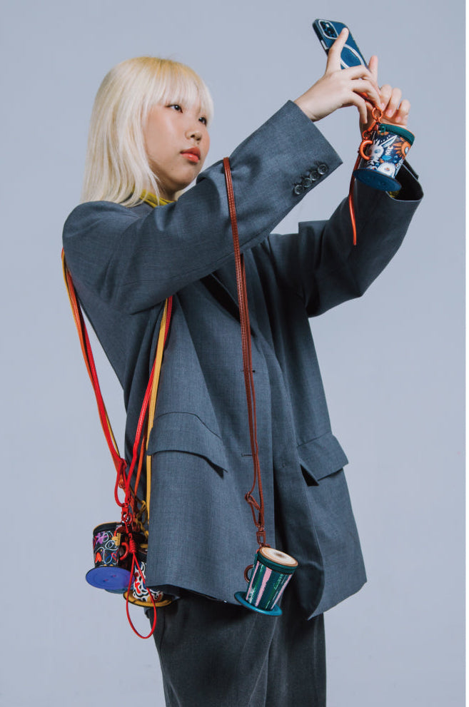 Person holding a phone with colorful straps against a gray background